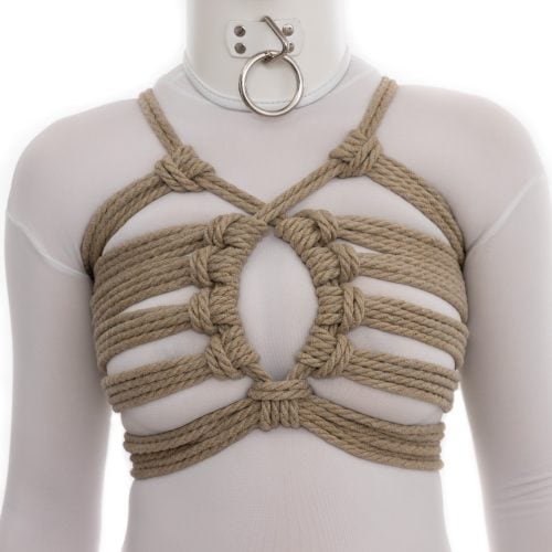 A picture of a woman wearing a white catsuit and white collar. She is also wearing a rope harness on her chest. This one features a series of horizontal straps that hold the ropes open in an oval or circular arrangement, somewhat like a Moon Gate.