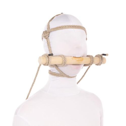 A female model in a white zentai has a rope harness on her head tied to a wooden dowel in her mouth. It is a pony play style harness with the ends of the rope attached as reigns to the bit gag.